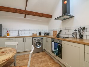Una cocina compacta con lavadora, horno y una mesa de madera.