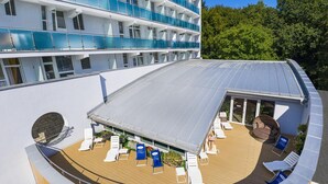 A cruise ship deck with a covered outdoor area featuring sun loungers, a seating area, and a glass balustrade. - Lech Sanatorium Uzdrowiskowe (Kolobrzeg)