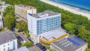 A multi-story hotel with a rooftop parking area and solar panels, located near a beach with a clear view of the ocean. - Lech Sanatorium Uzdrowiskowe (Kolobrzeg)