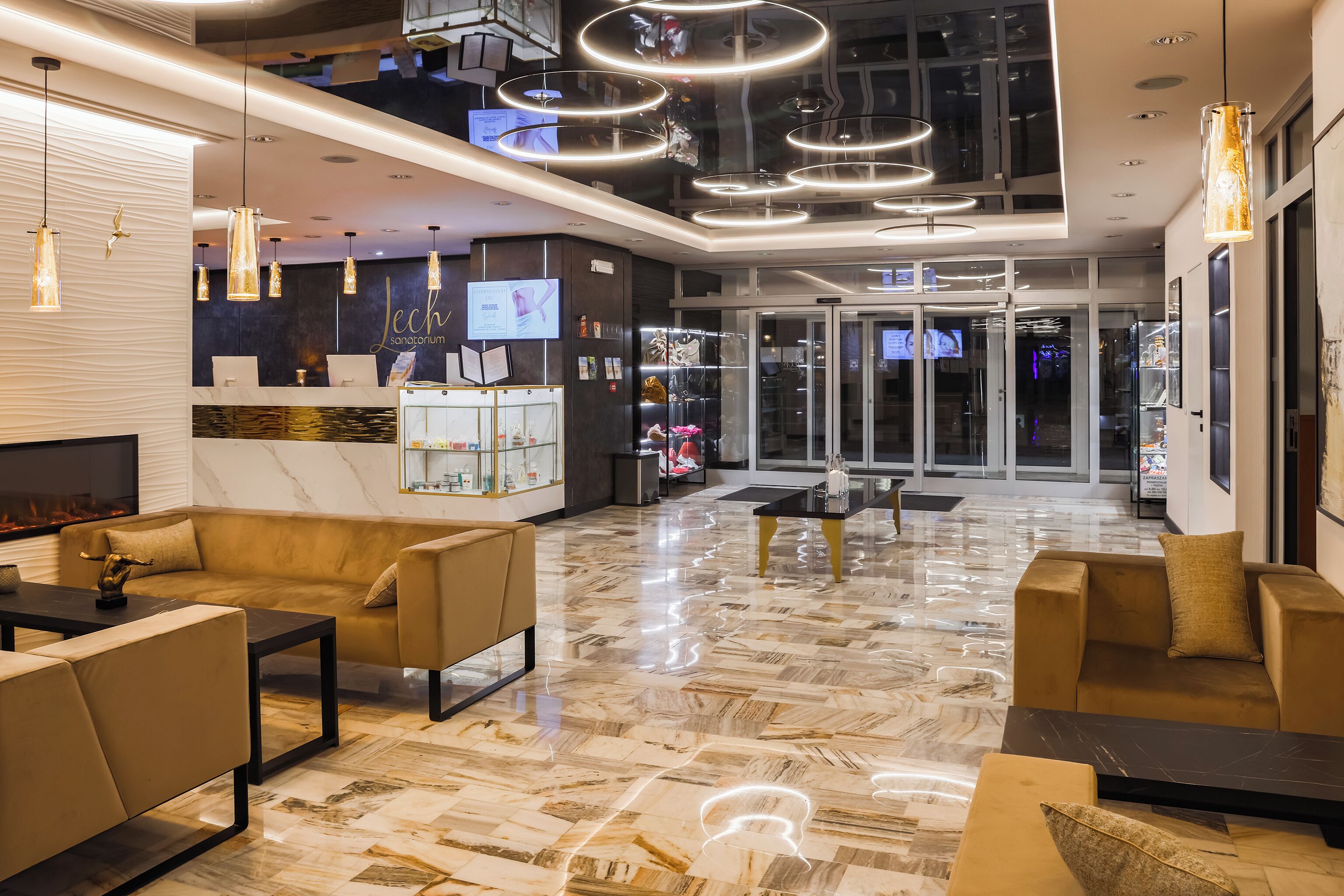 A modern lobby with a marble floor, sofas, a reception desk, and a TV screen.
