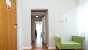 A hallway with a wooden door, a green armchair, and a painting on the wall. - Lech Sanatorium Uzdrowiskowe (Kolobrzeg)