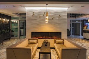 Una sala moderna con chimenea, dos sofás, una mesa de centro y una pared decorativa con siluetas de pájaros.
