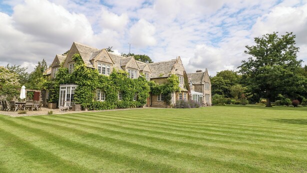 A large stone building with multiple windows and a well-maintained lawn in front. - Home Farm (Witney)