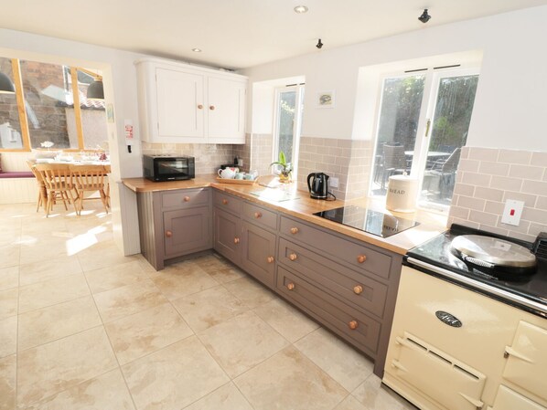 A modern kitchen with grey cabinets, a black microwave, and a black stove. There is a window with a view of the outside. - Pear Tree House (Whitby)