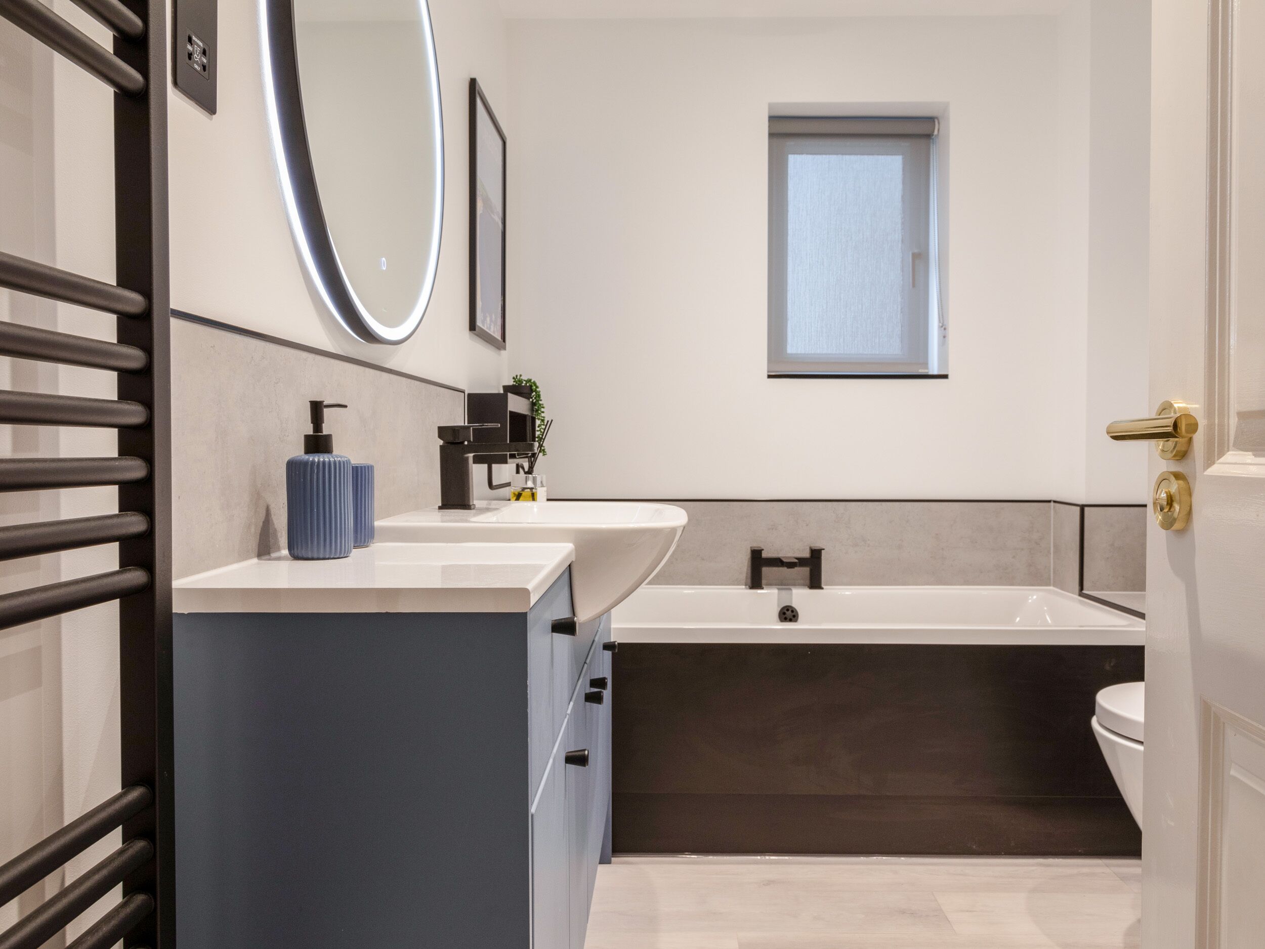 A modern bathroom with a bathtub, a sink with a soap dispenser, and a mirror.