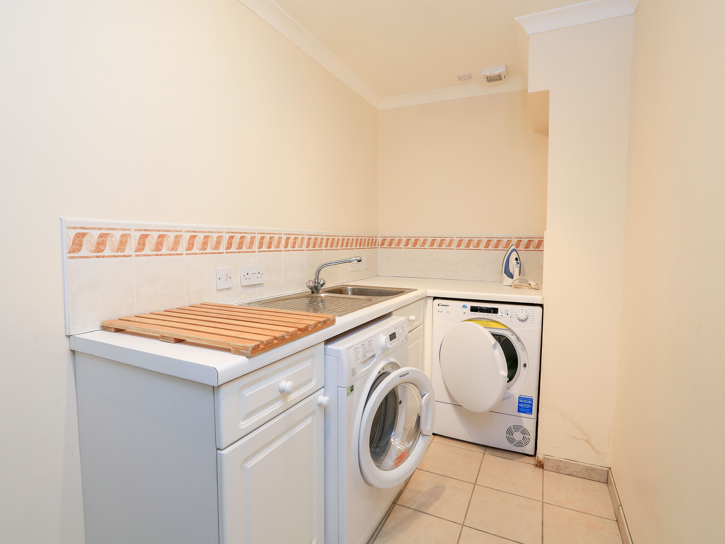 A compact laundry room with a washing machine, a drying rack, and a sink.