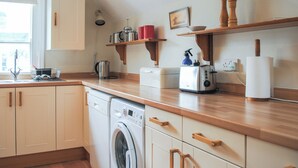 Une cuisine avec des meubles de rangement en bois, un lave-linge, un grille-pain et une fenêtre donnant sur un beau paysage.