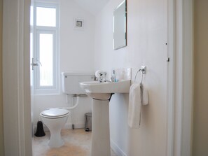 A small, white bathroom with a toilet, sink, and a mirror on the wall. - 7 Glenthorne House (Salcombe)