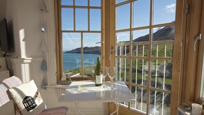 A cozy room with a large window offering a scenic view of the sea and hills. - 9 Prospect House (Kingsbridge)