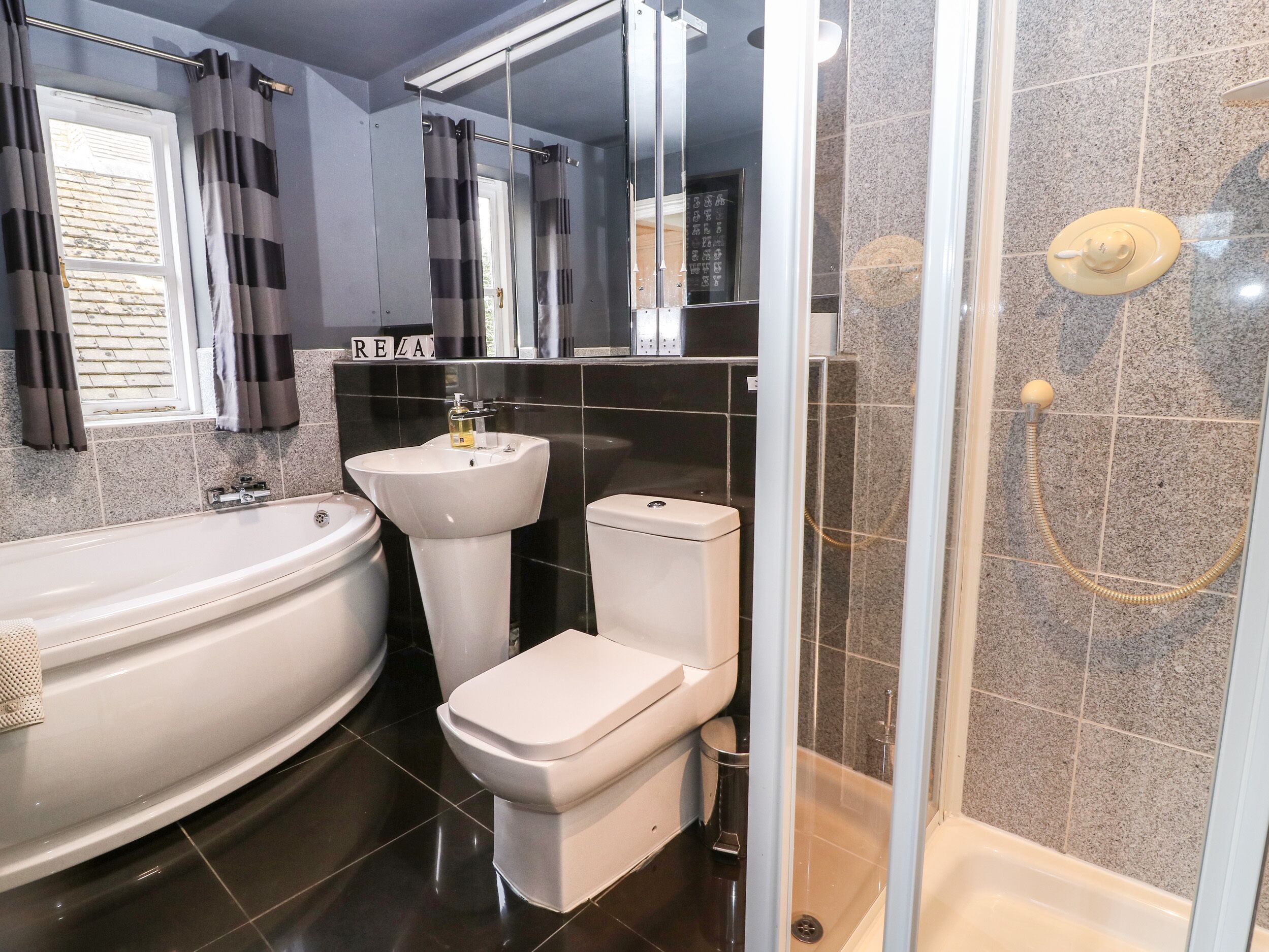 A modern bathroom with a bathtub, toilet, and shower.