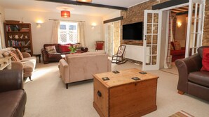 A cozy living room with a fireplace, a television, and a bookshelf. - South Hill Farmhouse (Cheltenham)