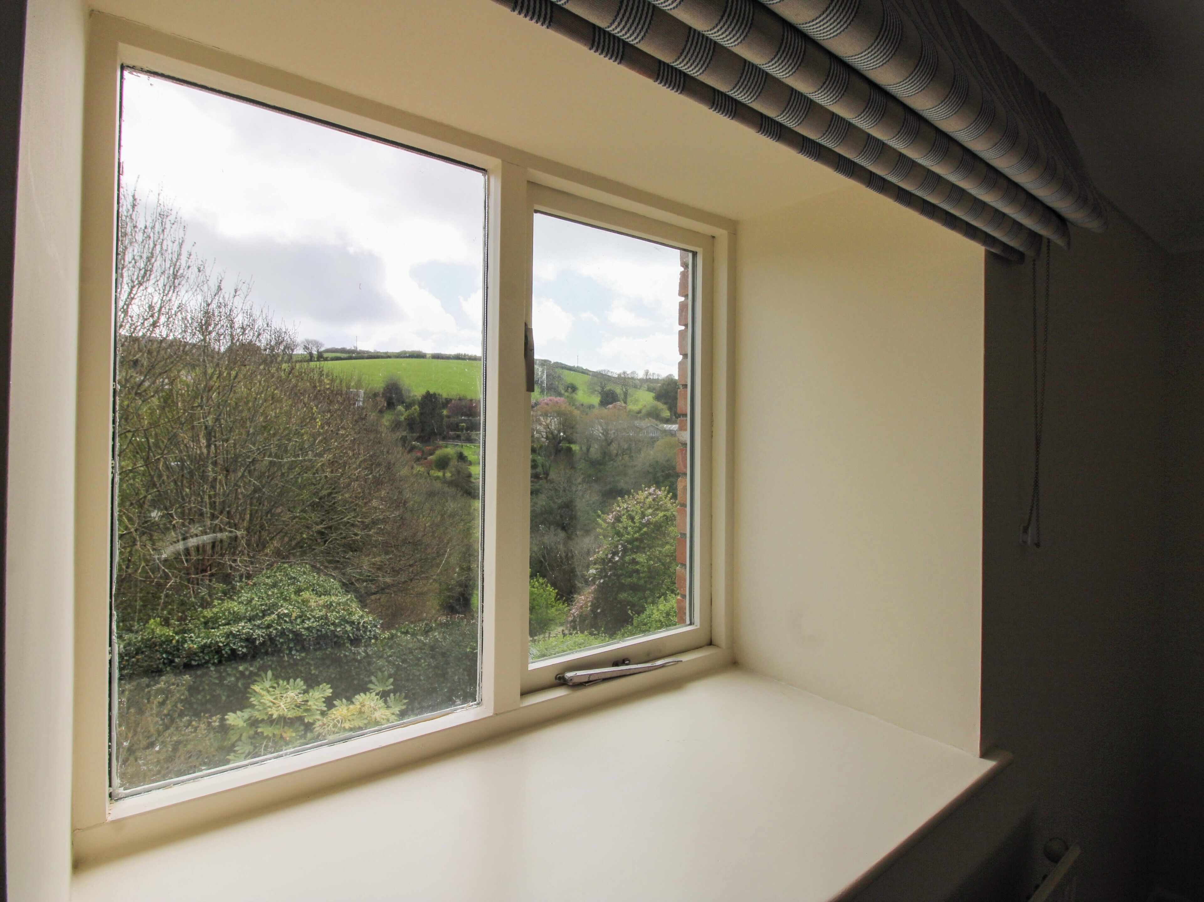 A room with a large window overlooking a green landscape.