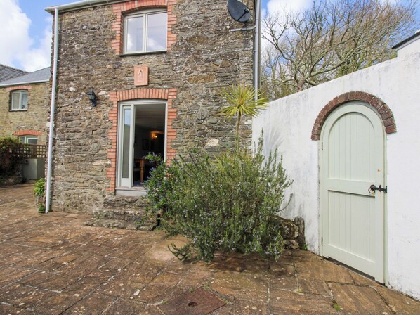 Un bâtiment en pierre avec une porte blanche et une fenêtre.