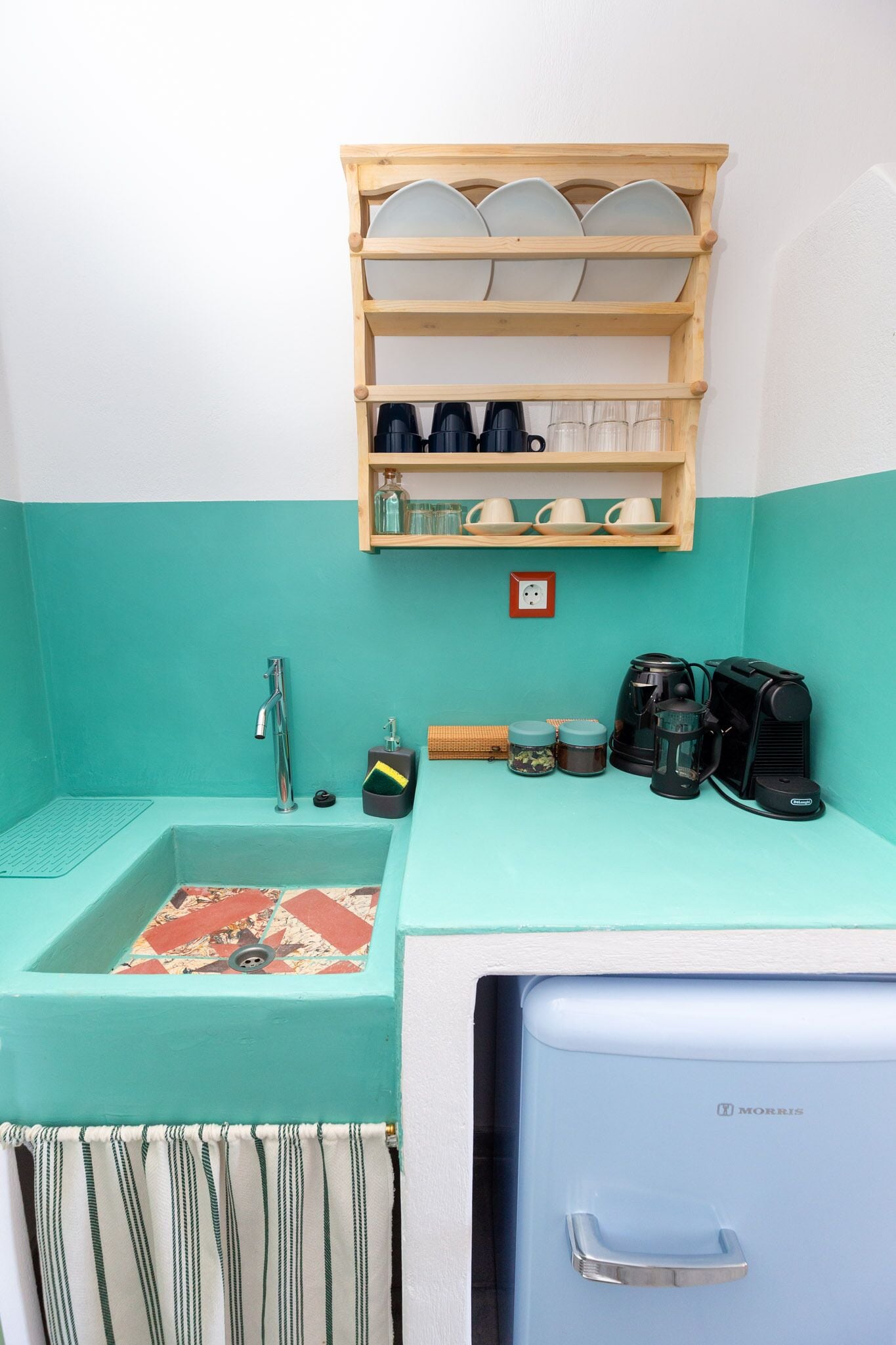 A compact kitchenette with a sink, a coffee maker, and a small refrigerator.