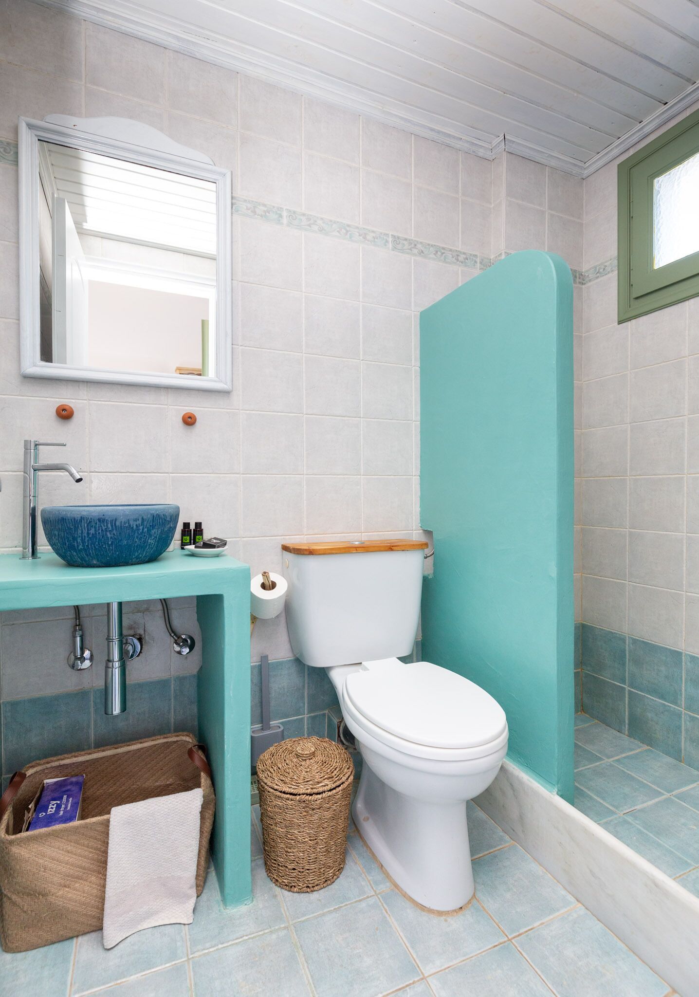 A bathroom with a blue sink, white toilet, and a green shower enclosure.
