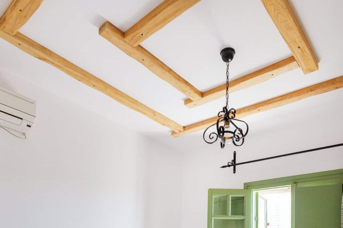A bedroom with a bed, a hanging light fixture, a green door, and a white wall.