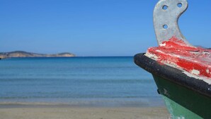 A boat with a metal part and red paint on a beach. - Ailouros summer hotel (Naxos)