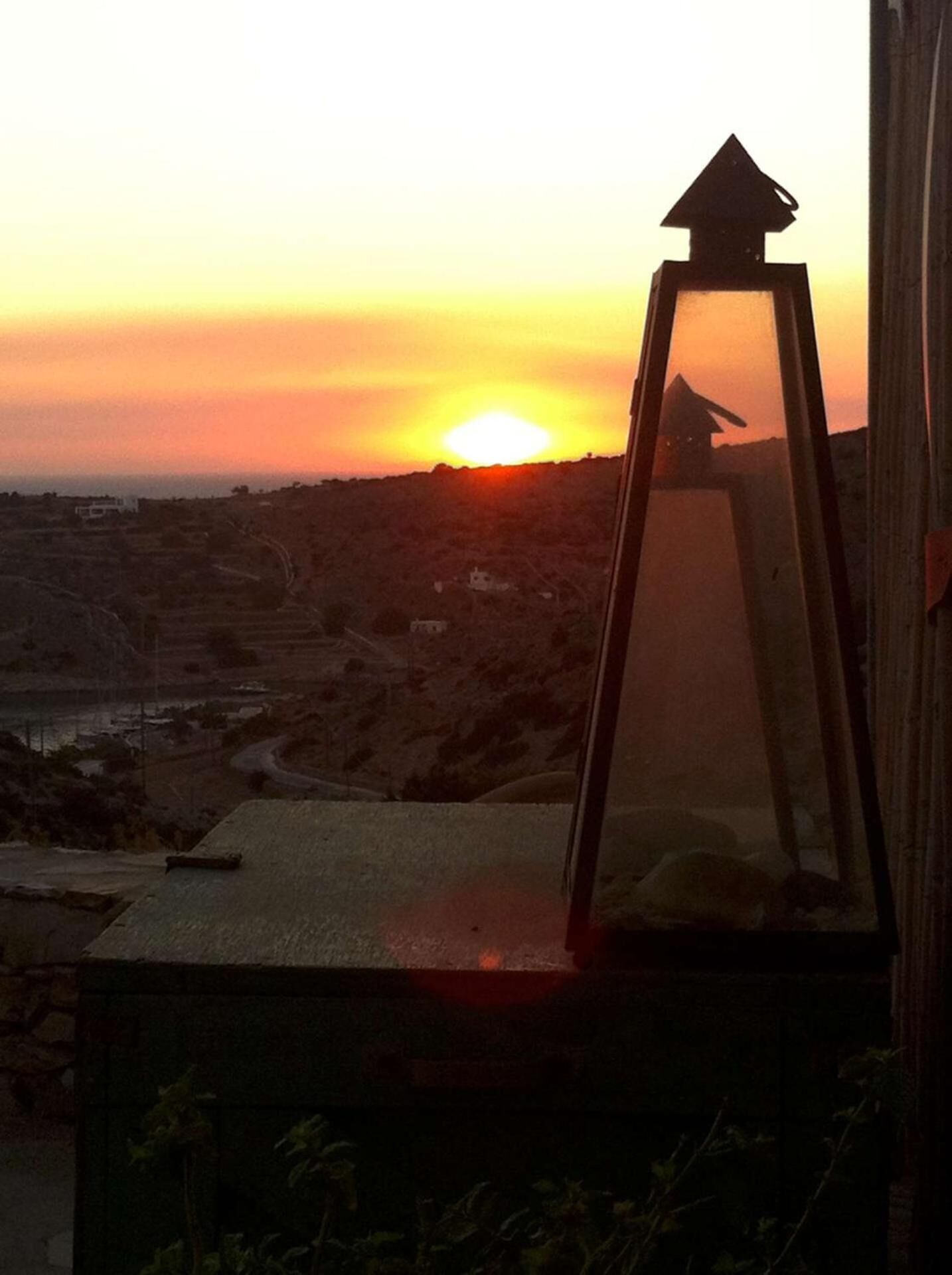 A sunset view from a window with a lantern in the foreground.