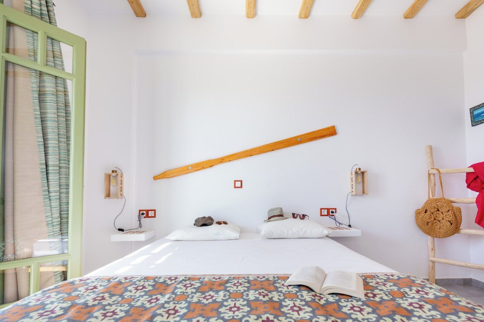 Een minimalistisch slaapkamer met een bed, nachtkastjes en een houten balk aan het plafond.