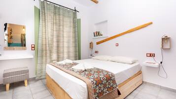 Ein Schlafzimmer mit einem hölzernen Bett, einem grünen Vorhang, einem Nachttisch mit Büchern und einer Wandleuchte.