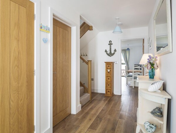 A hallway with wooden flooring, a staircase, a wooden cabinet, and a mirror on the wall. - 3 Ocean Reach (Kingsbridge)