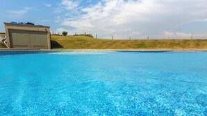 Une piscine aux eaux cristallines, avec une pelouse et un bâtiment en arrière-plan.