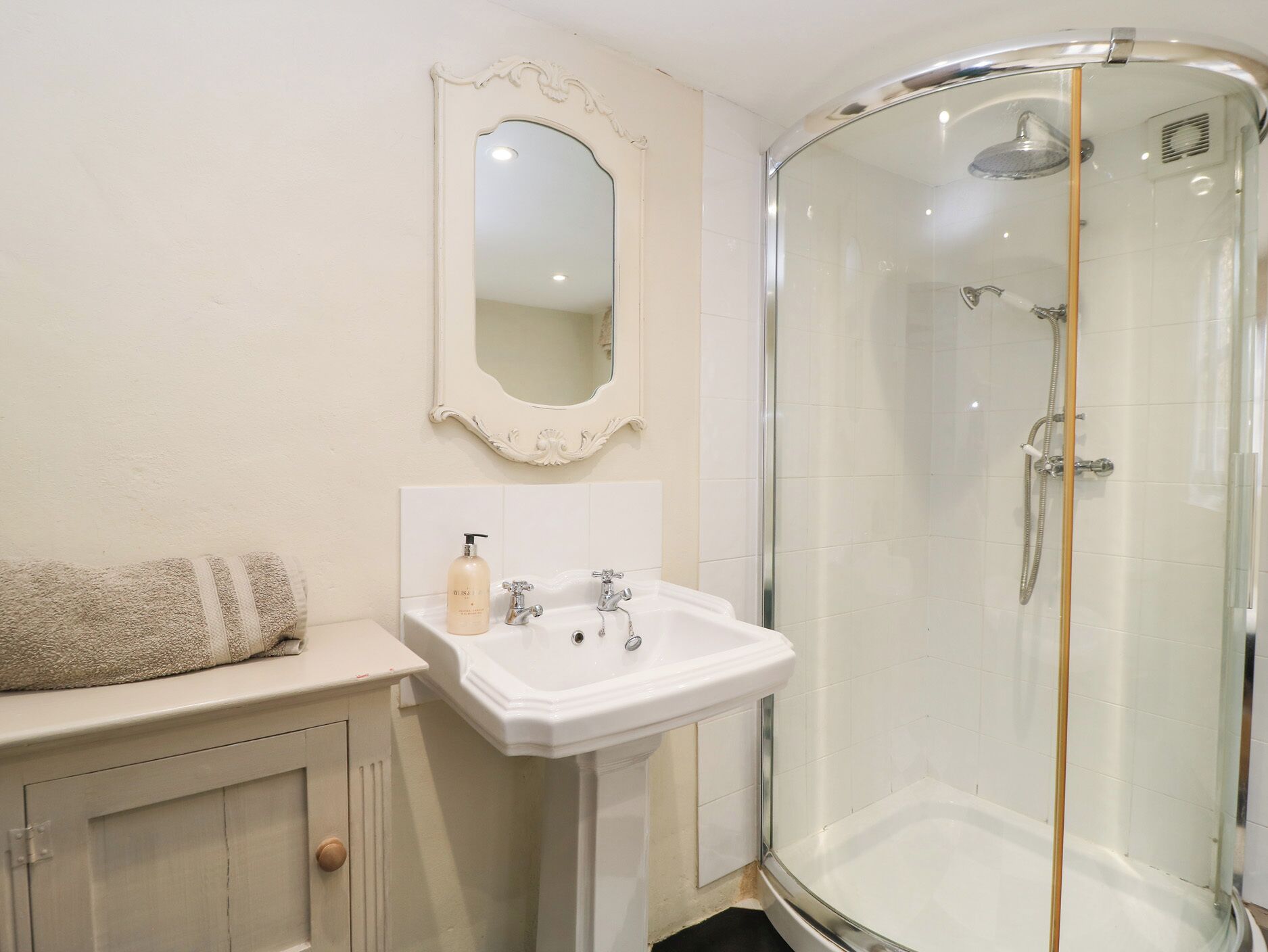 A bathroom with a white sink, a mirror, and a glass-enclosed shower.
