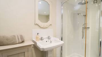A bathroom with a white sink, a mirror, and a glass-enclosed shower.