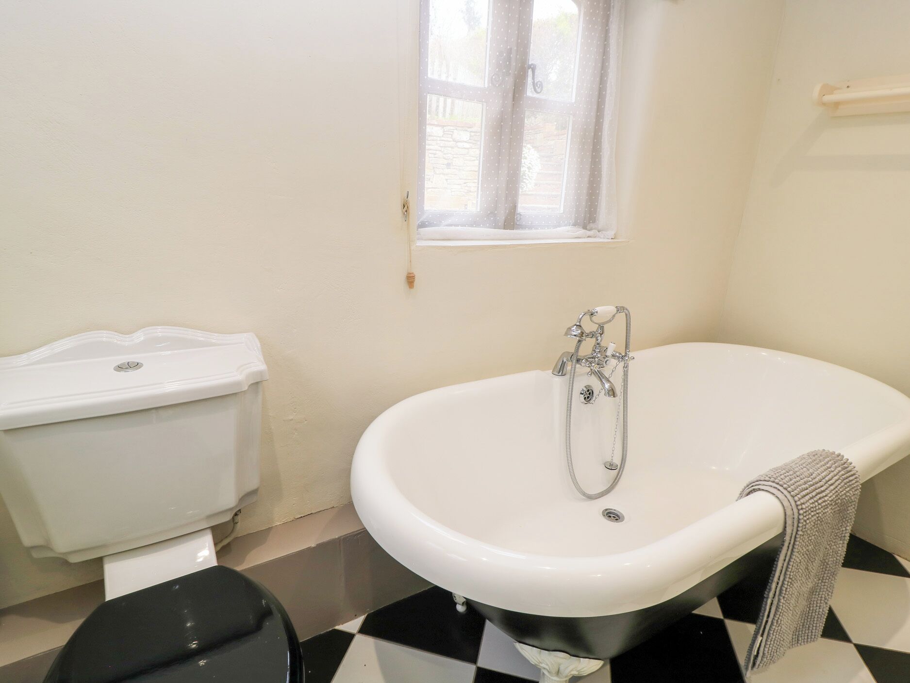Ein Badezimmer mit einer weißen Badewanne, einer Toilette und einem Fenster.