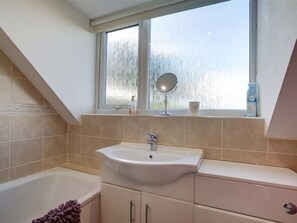 Ein Badezimmer mit einer Badewanne, einem Waschbecken und einem Fenster über dem Waschbecken.