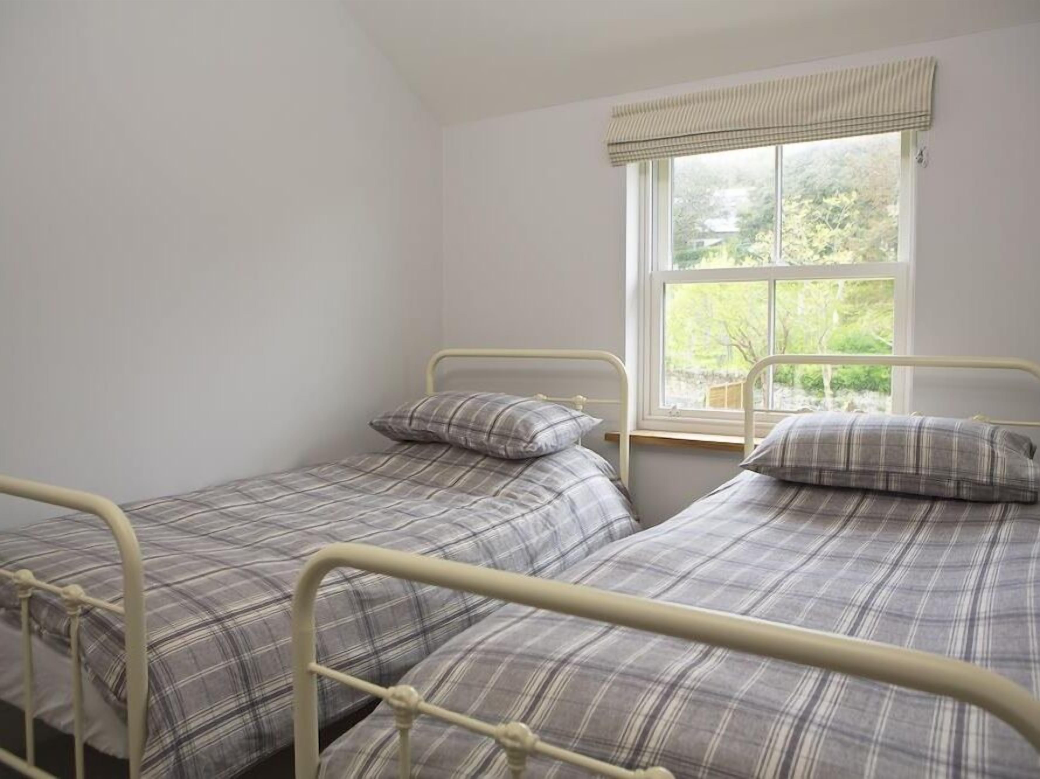 Une chambre à coucher avec deux lits jumeaux, chacun recouvert d’une couette à carreaux et agrémenté d’oreillers assortis.
