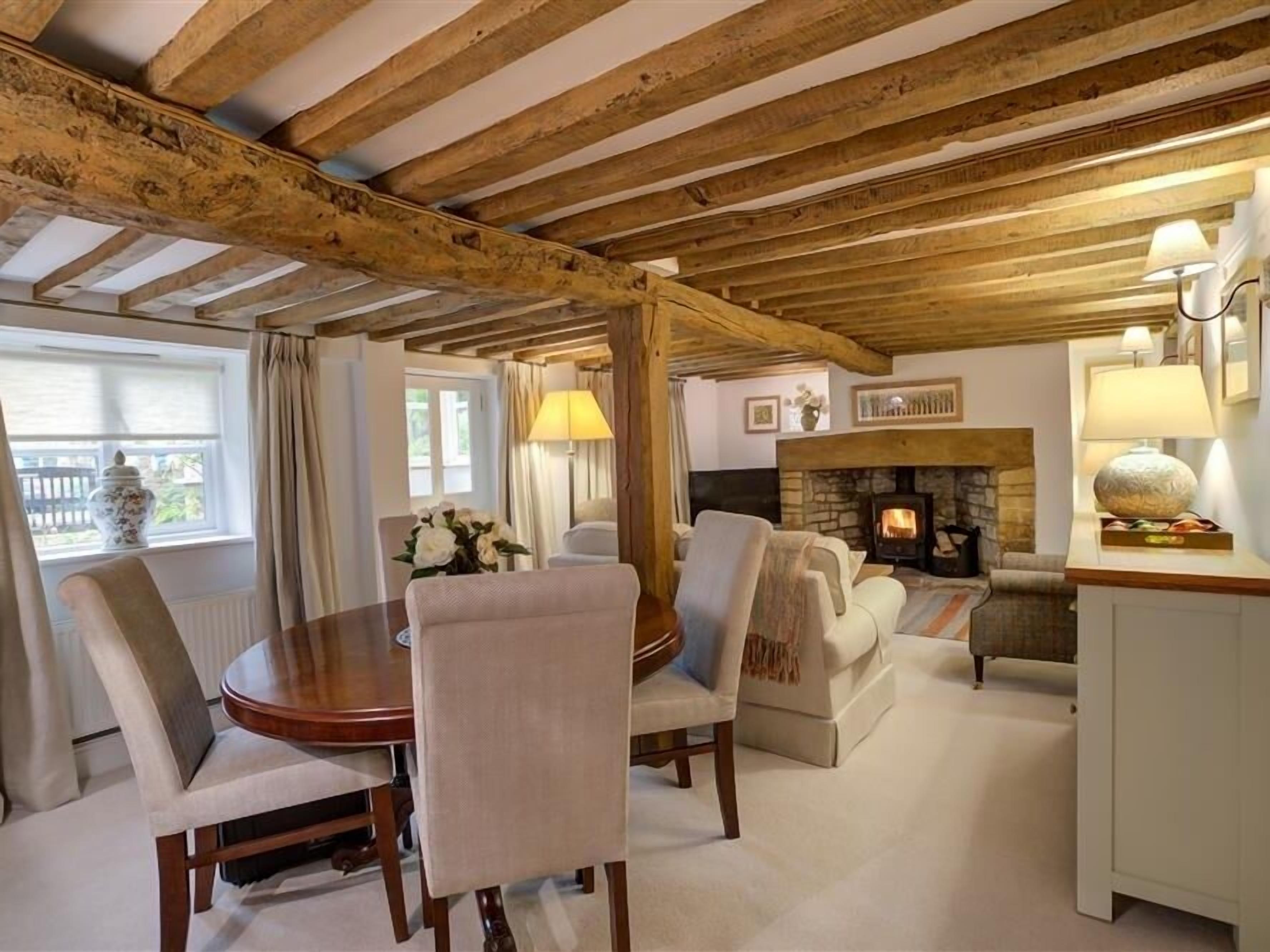 A cozy living room with a fireplace, wooden beams, and comfortable seating.