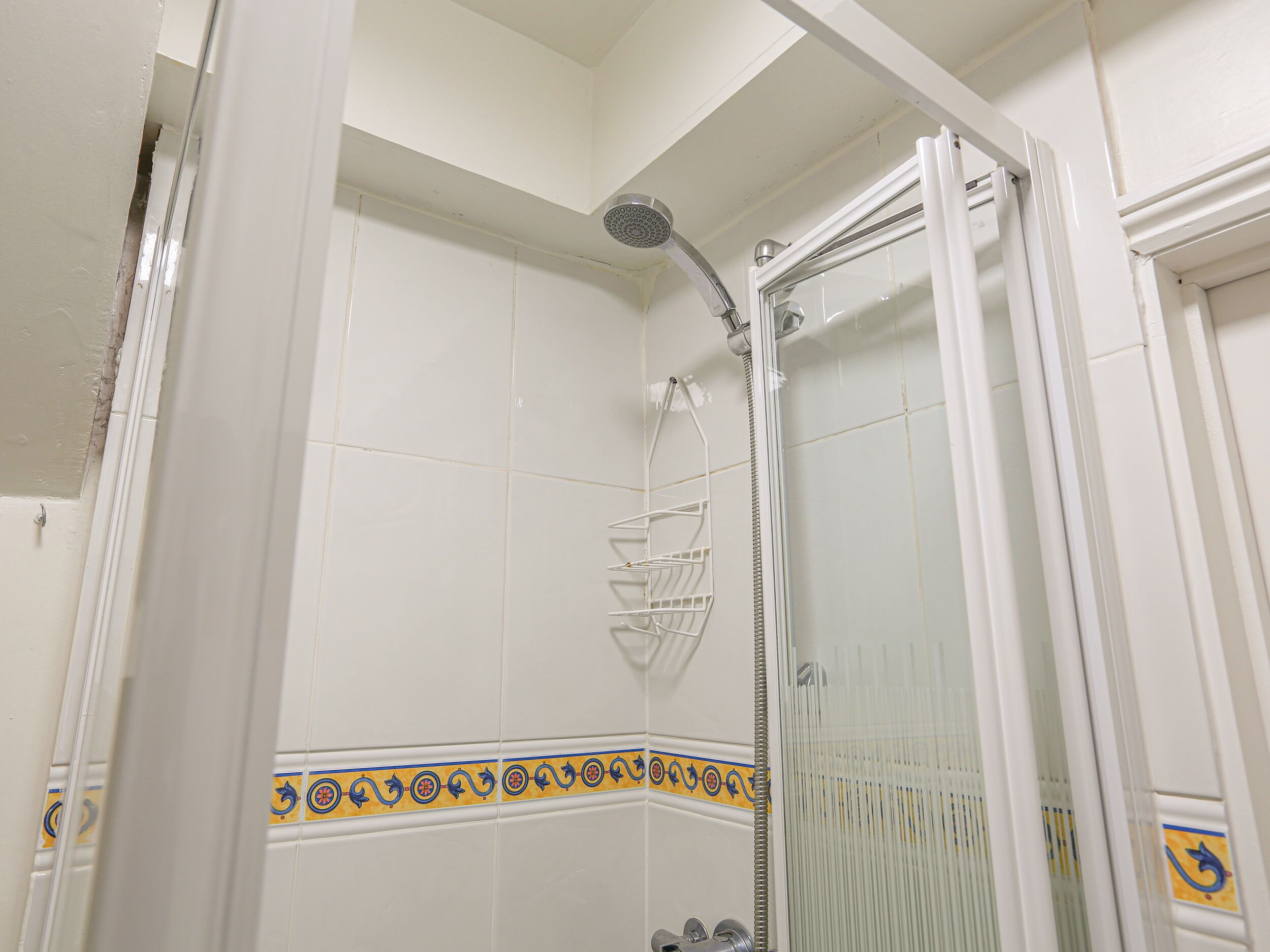 A shower with a glass door and a metal showerhead.
