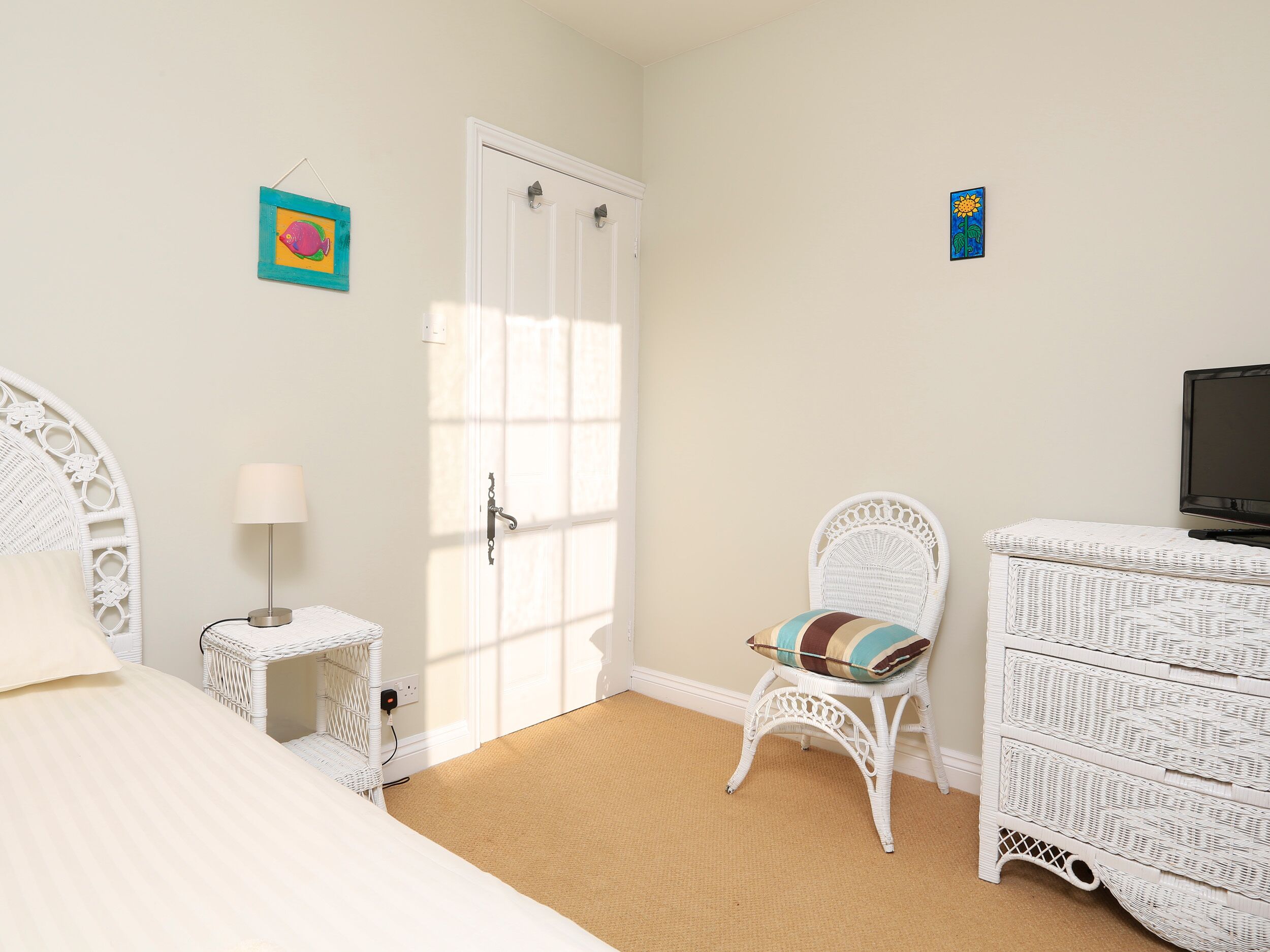 A bedroom with a bed, a chair, a dresser, and a television.