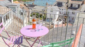 A balcony with a table and chairs overlooking a harbor with boats. - Upper Marcam House (Salcombe)