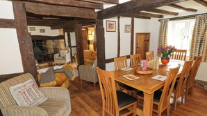 A cozy room with a wooden dining table, chairs, a sofa, and a fireplace. - Elmhurst Cottage (Stratford-upon-Avon)