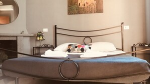 A neatly made bed with a checkered bedspread, a colorful pillow, and a painting of a woman on the wall. - Old Bakery Guest house (Rome)