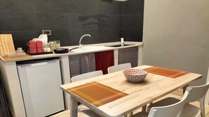A compact kitchen with a dining area, featuring a sink, a dishwasher, and a table with chairs. - Old Bakery Guest house (Rome)