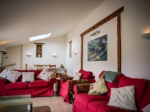 Una sala de estar con sofás rojos, una mesa de comedor y un cuadro en la pared.