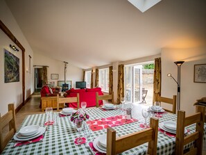Un comedor con mantel a cuadros, sillas de madera y un sofá rojo al fondo.