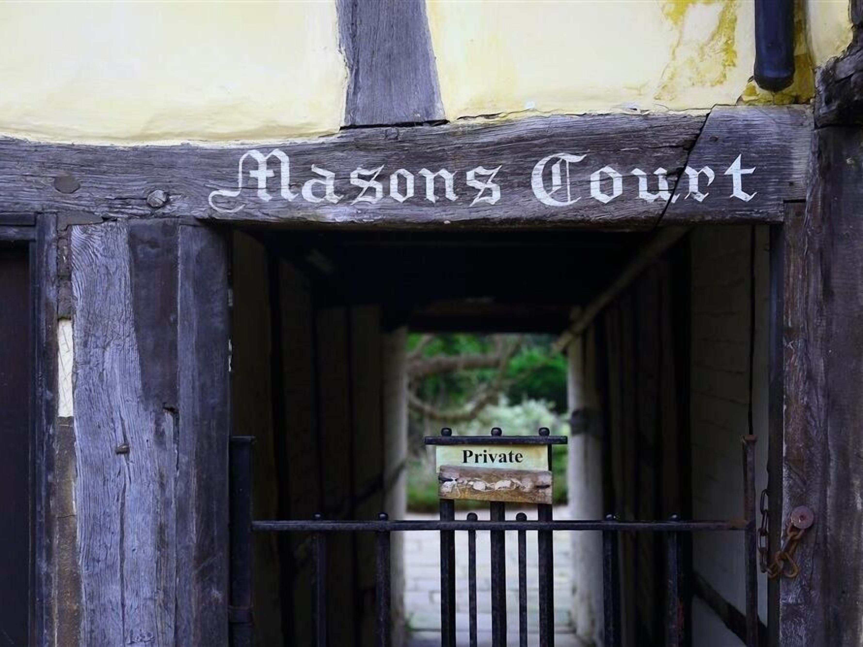 Una entrada de madera con un letrero que dice "Masons Court" y un letrero que indica "Privado".