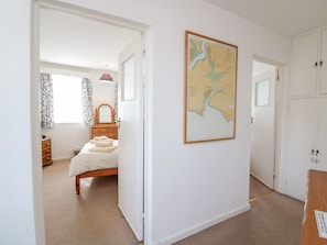 A bedroom with a bed, a dresser, a mirror, and a map on the wall.