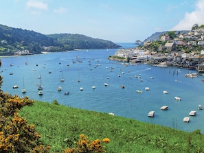 A coastal town with numerous boats in the water, a hilly landscape, and buildings along the shore.