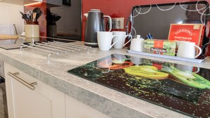 Una cocina moderna con encimera, hervidor, tazas y una caja de galletas tipo shortbread.