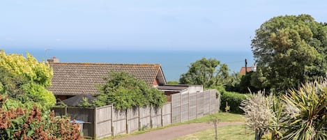 A residential property with a paved driveway, a wooden fence, and a view of the sea.