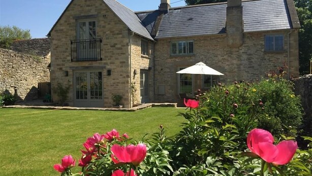 A stone house with a large balcony and a well-maintained lawn. - Hillside Cottage (Burford)