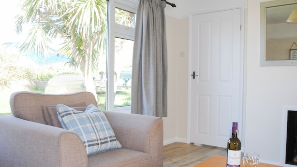 A living room with a sofa, a table with a bottle and glasses, and a door. - Bankside (Kingsbridge)