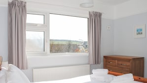 A bedroom with a bed, a dresser, and a window with curtains. - Bankside (Kingsbridge)