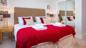 A hotel room with a large bed, two bedside tables, a mirror, and framed pictures on the wall. - 4 Dart Marina (Dartmouth)