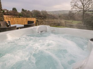 A hot tub with a warning sign, surrounded by wicker furniture and a stone wall. - The Cottage, Beeston Hall (Sowerby Bridge)